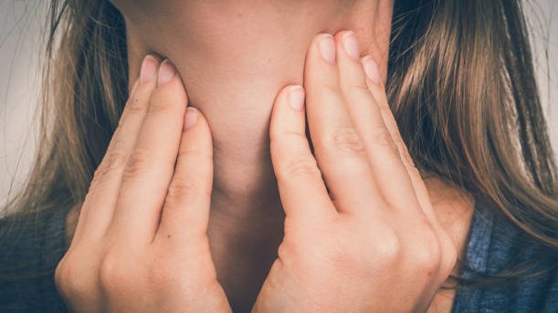 Femme aposant ses mains au niveau de sa thyroïde